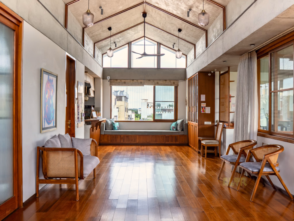 The main hall from the other end, with a long cushioned window seat and cane chairs on a wooden floor